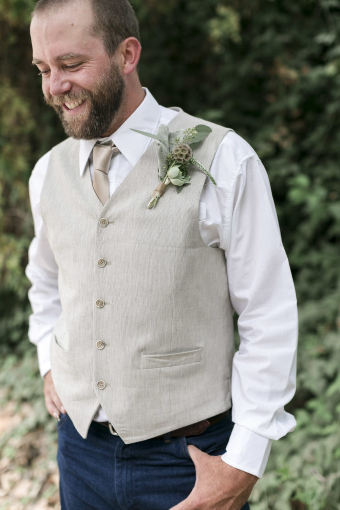 groom smiling laughing on wedding day in tan vest with boutonniere 