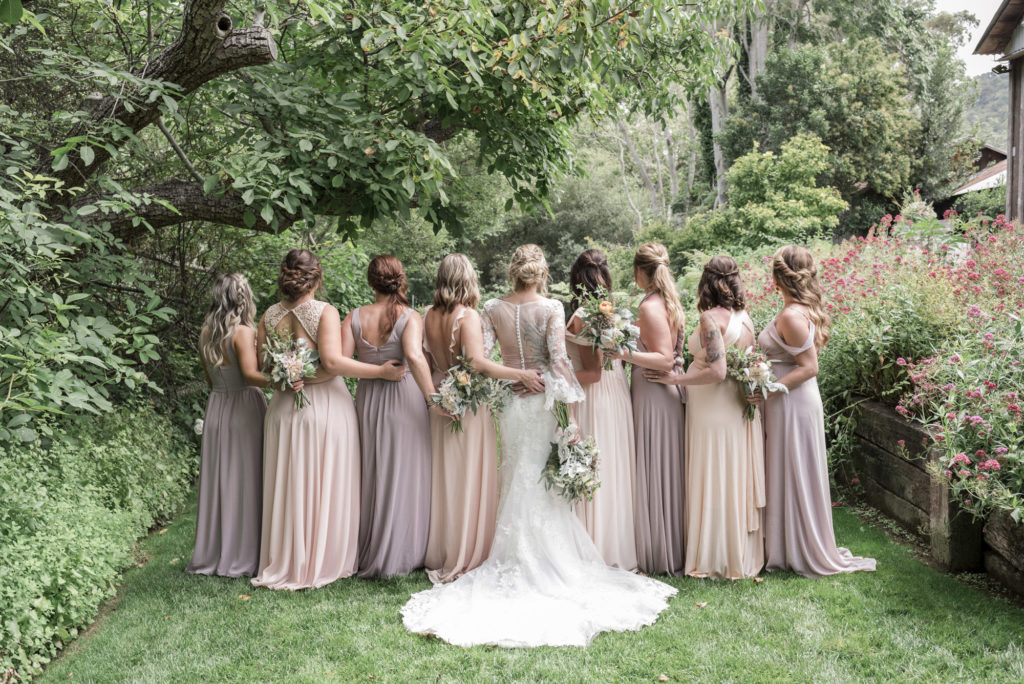 Bride and bridesmaids in shades of blush in a garden setting