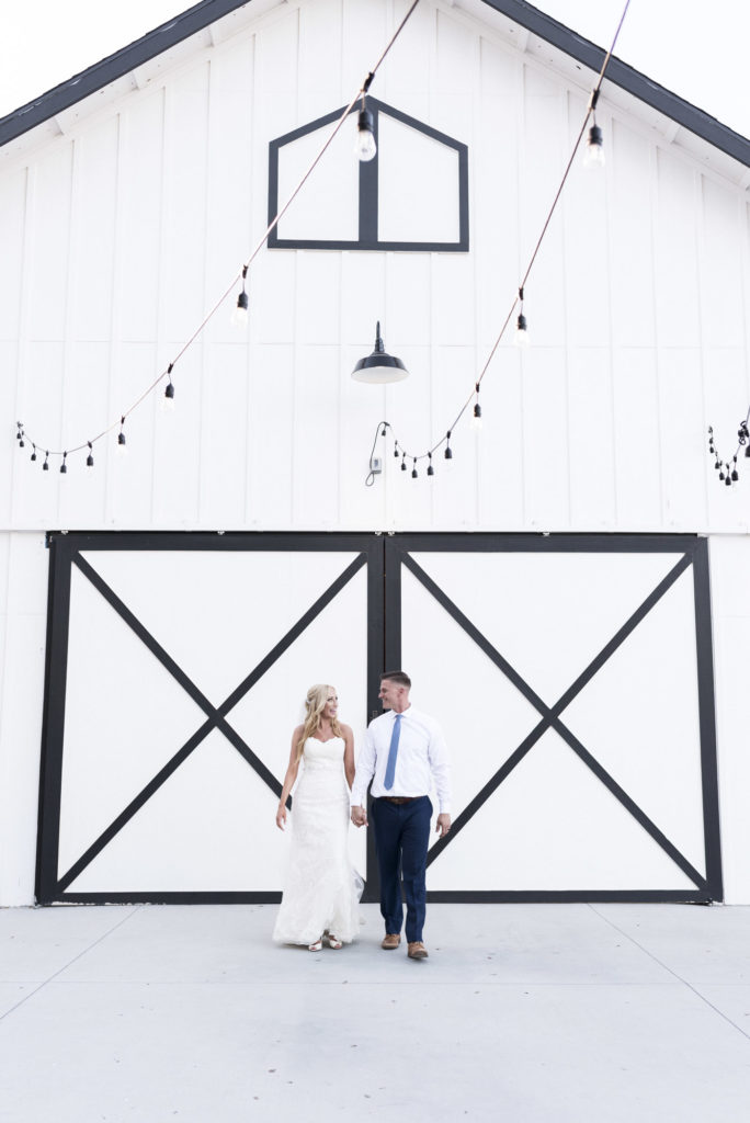 bride and groom in front of white barn doors