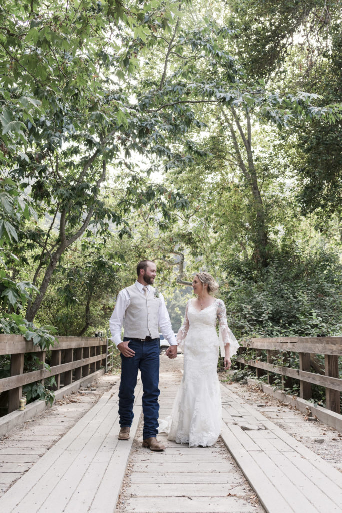 bride and groom holding hands walking on wooden bridge