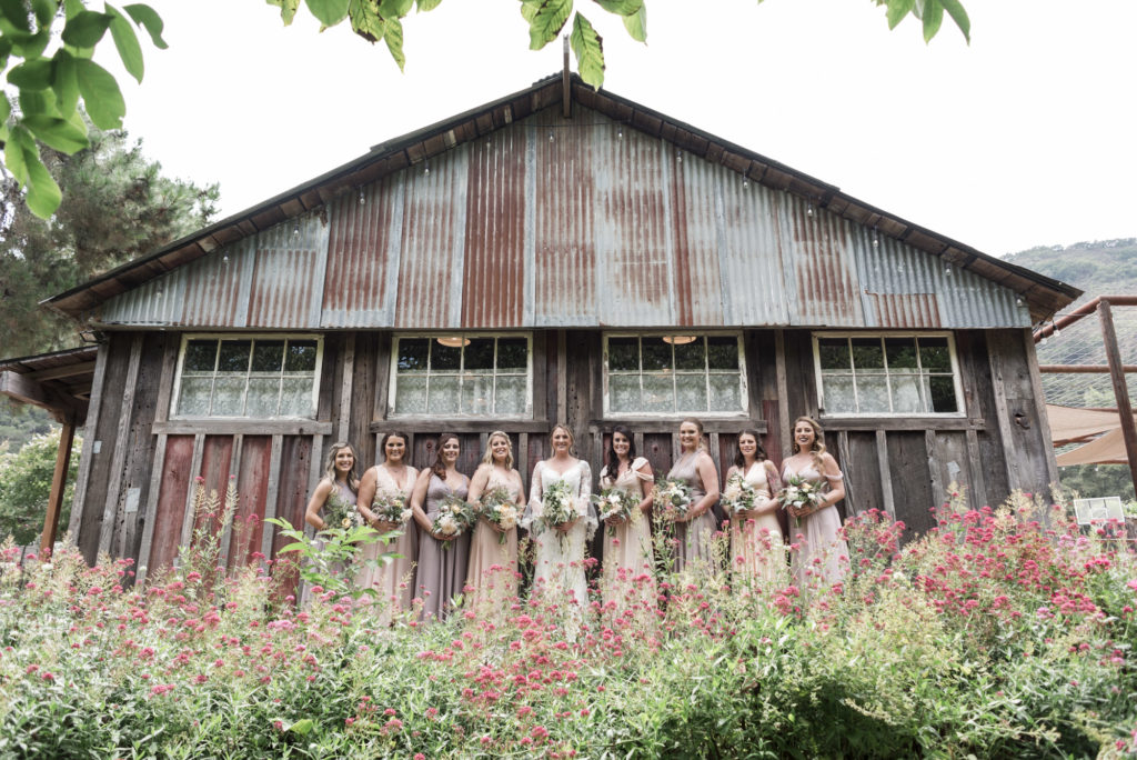 bride and bridesmaids in front of rustic bridal suite barn