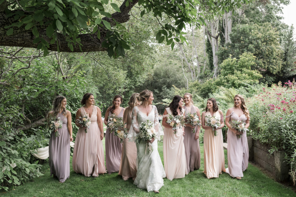 bride and bridesmaids walking through garden in shades of blush