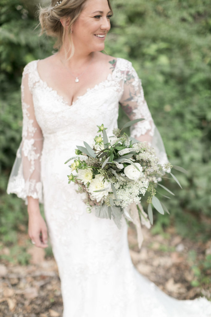 bride holding soft white wedding bouquet in vintage lace wedding dress